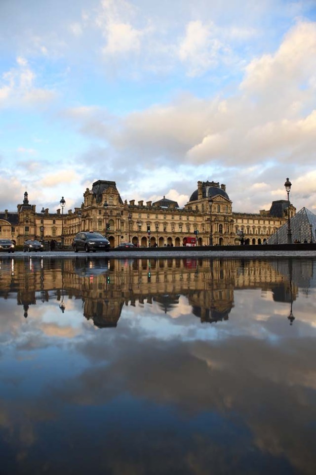 The Richelieu wing (Rear) and the pyramid of the Louvre Museum are reflected in a pool of rain water on January 1, 2018 in Paris. / AFP PHOTO / GUILLAUME SOUVANT