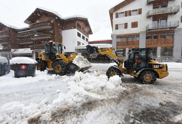 Workers remove snow beside the Zermatt train station after heavy snowfall and avalanches trapped more than 13,000 tourists at Zermatt, which is one of Switzerland's most popular ski stations on January 09, 2018. The snow has blocked all roads and the train leading to the resort in the southern Swiss canton of Valais, which was also hit by some power outages. / AFP PHOTO / Mark Ralston