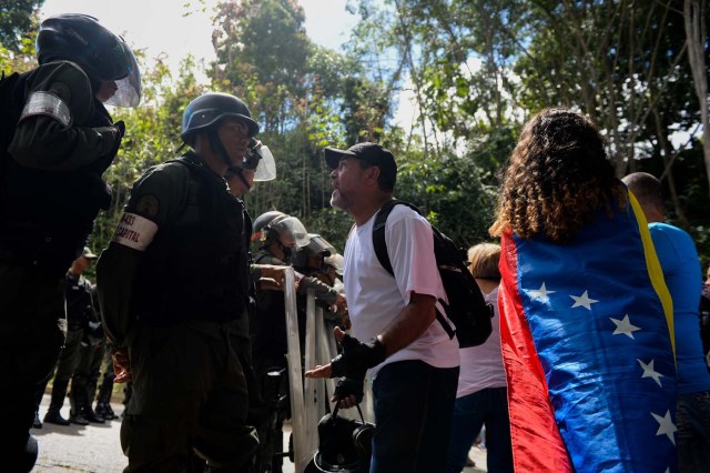 An activist opposing Venezuelan President Nicolas Maduro argues with security forces blocking their access to the funeral of Jose Diaz Pimentel and Abraham Agostini, two of the six other dissidents gunned down along with former elite police officer Oscar Perez in a bloody police operation, at a cemetery in Caracas on January 20, 2018. Perez, Venezuela's most wanted man since June when he flew a stolen police helicopter over Caracas dropping grenades on the Supreme Court and opening fire on the Interior Ministry, had gone on social media while the operation was under way on January 16 to say he and his group wanted to surrender but were under unrelenting sniper fire. That has raised questions about the government's account that the seven were killed after opening fire on police who had come to arrest them. / AFP PHOTO / Federico PARRA