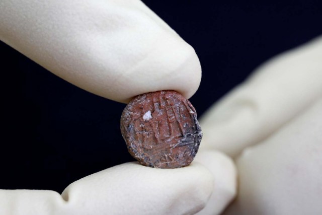 A conservator shows a 2,700-year-old clay seal impression which archaeologists from the Israel Antiquities Authority say belonged to a biblical governor of Jerusalem and was unearthed in excavations in the Western Wall plaza in Jerusalem's Old City January 1, 2018. REUTERS/Nir Elias