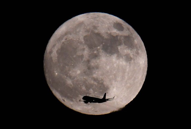 A passenger plane, with a 'supermoon' full moon seen behind, makes its final landing approach towards Heathrow Airport in London, Britain, January 1, 2018. REUTERS/Toby Melville