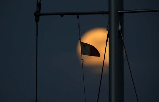 A Maltese flag flies from a yacht's mast as a 'supermoon' full moon rises in Pieta, Malta, January 1, 2018. REUTERS/Darrin Zammit Lupi