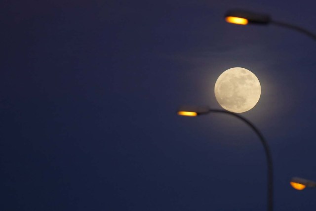 The 'supermoon' full moon is seen rising behind street lights in Ronda, southern Spain January 1, 2018. REUTERS/Jon Nazca