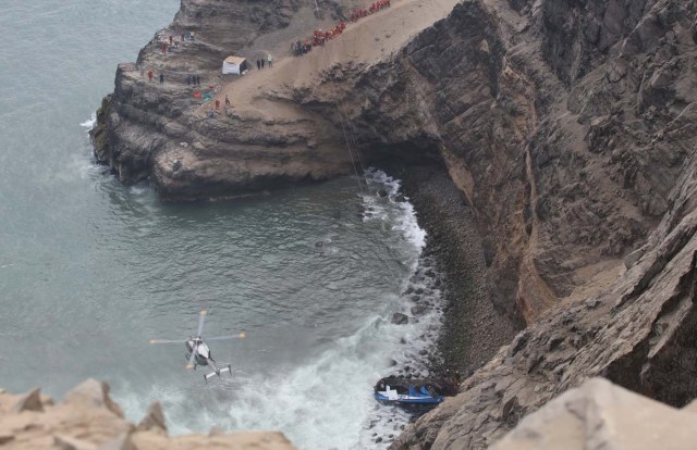 A helicopter helps rescue workers at the scene after a bus crashed with a truck and careened off a cliff along a sharply curving highway north of Lima, Peru, January 2, 2018. REUTERS/Guadalupe Pardo