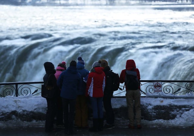 Visitors take pictures near the brink of the ice covered Horseshoe Falls in Niagara Falls, Ontario, Canada, January 3, 2018. REUTERS/Aaron Lynett