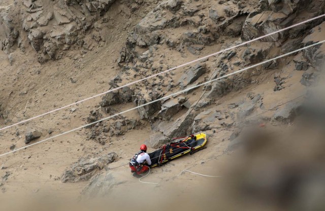 Rescue workers carry victims after a bus crashed with a truck and careened off a cliff along a sharply curving highway north of Lima, Peru, January 3, 2018. REUTERS/Guadalupe Pardo