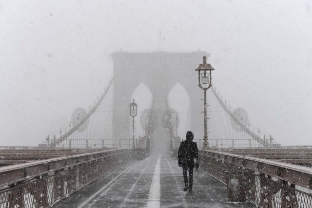 A pedestrian walks through blinding snow across the Brooklyn Bridge during Storm Grayson in New York City, U.S., January 4, 2018. REUTERS/Darren Ornitz