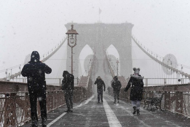 Pedestrians stop to take photos in snow and heavy winds as they walk across the Brooklyn Bridge during Storm Grayson in New York City, U.S., January 4, 2018. REUTERS/Darren Ornitz