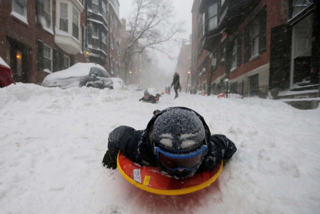 A boy sleds down a Beacon Hill street during Storm Grayson in Boston, Massachusetts, U.S., January 4, 2018. REUTERS/Brian Snyder