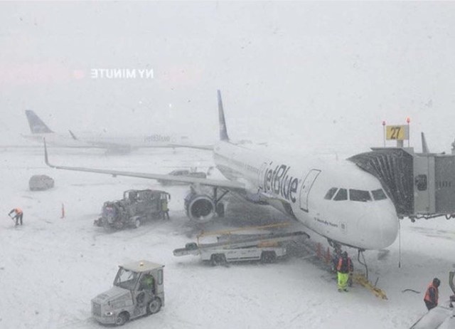 Staff work on next to a parked plane at John F. Kennedy International Airport during a snow storm, in Queens, New York, U.S. in this photo taken January 4, 2018 and obtained from social medi. Max Host via REUTERS THIS IMAGE HAS BEEN SUPPLIED BY A THIRD PARTY. MANDATORY CREDIT.NO RESALES. NO ARCHIVES