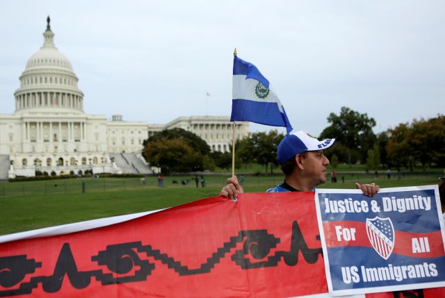FILE PHOTO: A Salvadoran man holds his nation's flag and a sign during a protest rally for immigrants rights on Capitol Hill in Washington, DC, U.S., October 8, 2013. REUTERS/Gary Cameron/File Photo