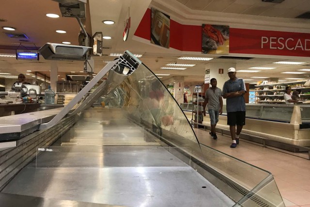 People walk past empty shelves at a supermarket in Caracas, Venezuela January 9, 2018. REUTERS/Marco Bello