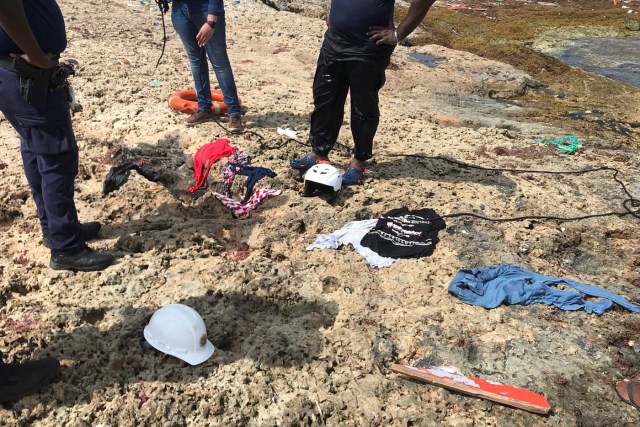 Police officers stand next to clothes recovered from water at the shore where bodies of four people were found, near Willemstad, Curacao January 11, 2018. REUTERS/Umpi Welvaart