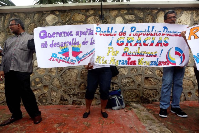 Venezuelan migrants hold signs reading "We want to contribute to the development of the Dominican Republic" and "People of the Dominican Republic, thank you for receiving us," as delegates of President Nicolas Maduro's government and Venezuela's opposition coalition meet for a round of talks, in Santo Domingo, Dominican Republic January 12, 2018. REUTERS/Roberto Guzman