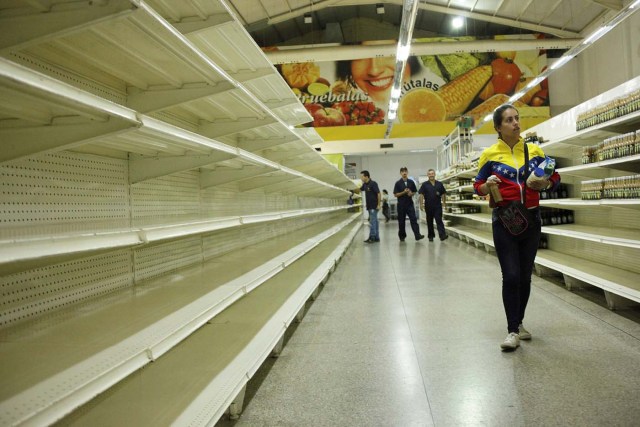 People walk past empty shelves at a supermarket in San Cristobal, Venezuela January 16, 2018. REUTERS/Carlos Eduardo Ramirez