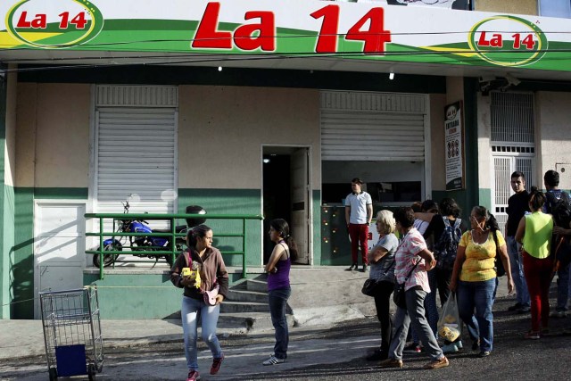 People line up outside a supermarket with its security shutters partially closed as a precaution against riots or lootings, in San Cristobal, Venezuela January 16, 2018. Picture taken January 16, 2018. REUTERS/Carlos Eduardo Ramirez