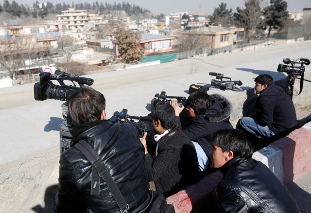Afghan journalists take cover as they film the site of an attack by gunmen in Kabul, Afghanistan, January 21, 2018. REUTERS/Omar Sobhani