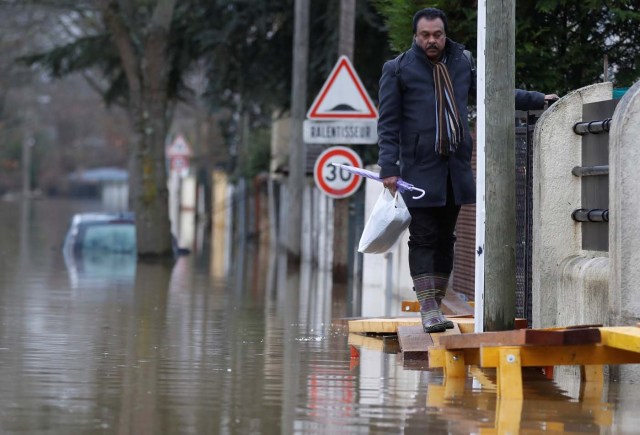 A resident leaves home in a flooded street of a residential area in Villeneuve-Saint-Georges, near Paris, France January 25, 2018. REUTERS/Christian Hartmann