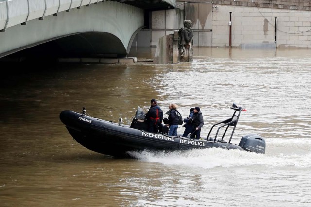 Paris police patrol on a small craft as they pass the Zouave statue as the Seine River rises after days of rainy weather in casues flooding in Paris, France, January 25, 2018. REUTERS/Gonzalo Fuentes