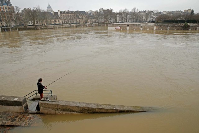 A man fishes on the flooded banks of the River Seine in Paris, France, after days of almost non-stop rain caused flooding in the country, January 27, 2018. REUTERS/Pascal Rossignol