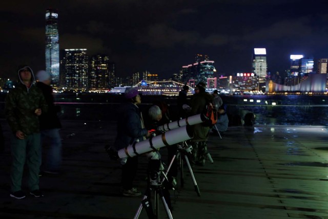 People set up telescopes on the waterfront for the super blue moon and eclipse in Hong Kong, China January 31, 2018. REUTERS/Bobby Yip