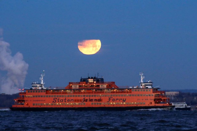 The "Super Blue Blood Moon" sets behind the Staten Island Ferry, seen from Brooklyn, New York, U.S., January 31, 2018. REUTERS/Eduardo Munoz