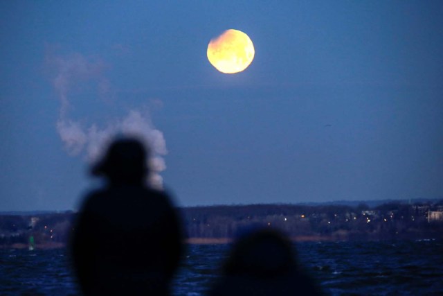 People watch the "Super Blue Blood Moon" as it sets while it is seen from Brooklyn, in New York, U.S., January 31, 2018. REUTERS/Eduardo Munoz