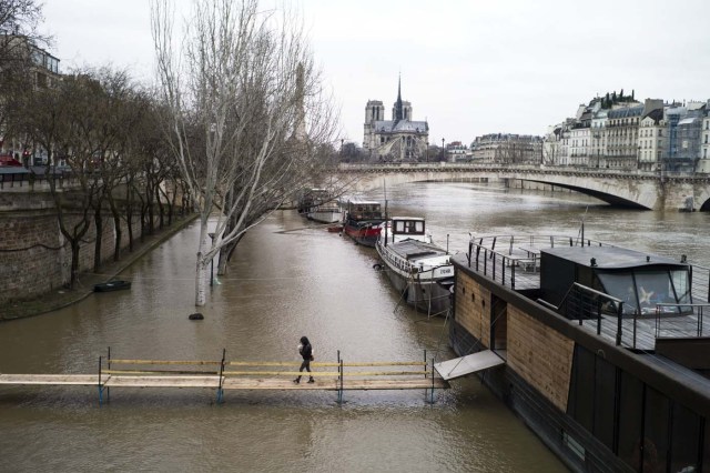 Paris (France), 07/01/2018.- A woman walks on a makeshift bridge submerged by floodwaters along the Seine river in Paris, France, 07 January 2018. The Seine river water level increased after the Storm Eleanor hit the country last week. (Francia) EFE/EPA/YOAN VALAT