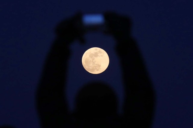 WU05. PEKÍN (CHINA), 31/01/2018.- Un hombre usa la cámara de su móvil para hacer una foto de la llamada superluna azul en Pekín, China, hoy, 31 de enero de 2018. Millones de personas aguardan hoy al eclipse total de la superluna azul, la segunda luna llena del mes y en su posición más cercana a la Tierra, fenómeno que se podrá ver principalmente desde Norteamérica, Asia y Oceanía. Siempre que las condiciones atmosféricas acompañen, los interesados podrán ver cómo la luna se tiñe de color rojizo sin necesidad de usar gafas especiales, como en el caso de los eclipses solares.