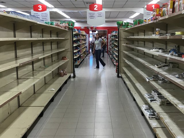 Una mujer pasa frente a estanterías vacías en un supermercado en Caracas, Venezuela, el 6 de enero de 2018. REUTERS / Marco Bello
