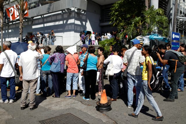 La gente espera en fila para comprar comida, en una acera frente a un supermercado en Caracas, Venezuela, el 6 de enero de 2018. REUTERS / Marco Bello