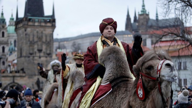 Men dressed as the Three Kings greet spectators as they ride camels during the Three Kings procession across the medieval Charles Bridge, as a part of a re-enactment of the Nativity scene, in Prague, Czech Republic January 5, 2018. REUTERS/David W Cerny