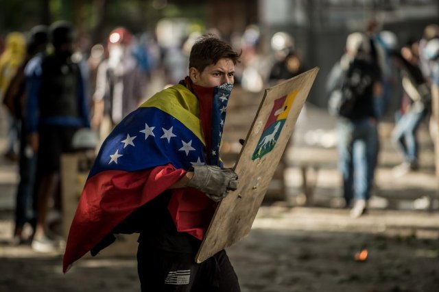 Manifestantes se protegen detrás de escudos caseros durante una protesta contra el gobierno en Caracas en julio de 2017. Credit Meridith Kohut para The New York Times