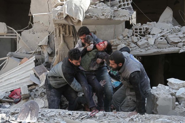 EDITORS NOTE: Graphic content / Syrians rescue a child following a reported regime air strike in the rebel-held town of Hamouria, in the besieged Eastern Ghouta region on the outskirts of the capital Damascus on February 21, 2018. / AFP PHOTO / ABDULMONAM EASSA
