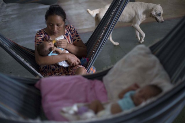Venezuelan Warao indigenous woman Yulen Moraleda, 33, gives milk to one of her new-born twins inside a shelter in the city of Boa Vista, Roraima, Brazil, on February 24, 2018. According with local authorities, around one thousand refugees are crossing the Brazilian border each day from Venezuela. With the constant influx of Venezuelan immigrants most are living in shelters and the streets of Boa Vista and Paracaima cities, looking for work, medical care and food. Most are legalizing their status to stay and live in Brazil. / AFP PHOTO / MAURO PIMENTEL