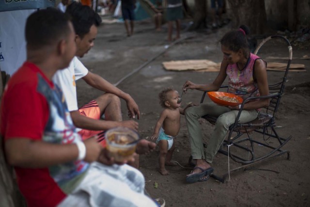A Venezuelan refugee feeds her son, at a shelter in the city of Boa Vista, Roraima, Brazil, on February 24, 2018. When the Venezuelan migratory flow exploded in 2017 the city of Boa Vista, the capital of Roraima, 200 kilometres from the Venezuelan border, began to organise shelters as people started to settle in squares, parks and corners of this city of 330,000 inhabitants of which 10 percent is now Venezuelan. / AFP PHOTO / MAURO PIMENTEL