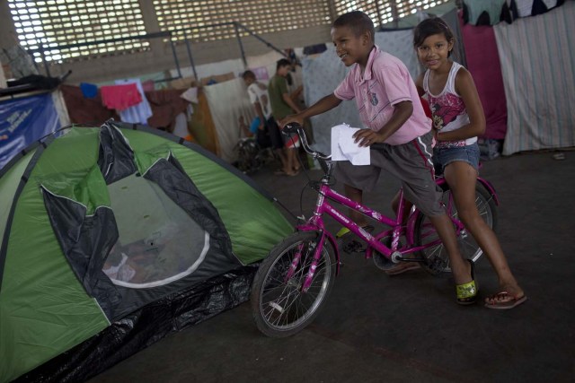 Venezuelan refugee children play at a shelter in the city of Boa Vista, Roraima, Brazil, on February 24, 2018. When the Venezuelan migratory flow exploded in 2017 the city of Boa Vista, the capital of Roraima, 200 kilometres from the Venezuelan border, began to organise shelters as people started to settle in squares, parks and corners of this city of 330,000 inhabitants of which 10 percent is now Venezuelan. / AFP PHOTO / MAURO PIMENTEL