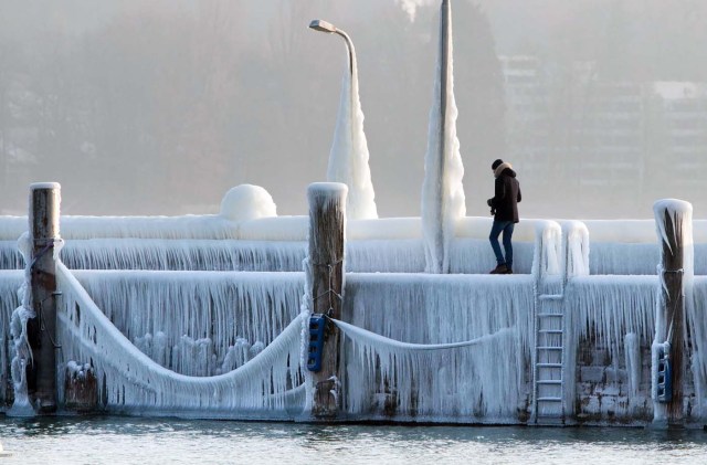 A man walks along a mole covered with ice and icicles on the Lake Constance on February 28, 2018 in Constance as a blast of Siberian weather dubbed the "Beast from the East" kept the mercury far below zero in huge parts of Europe. / AFP PHOTO / dpa / Steffen Schmidt / Germany OUT