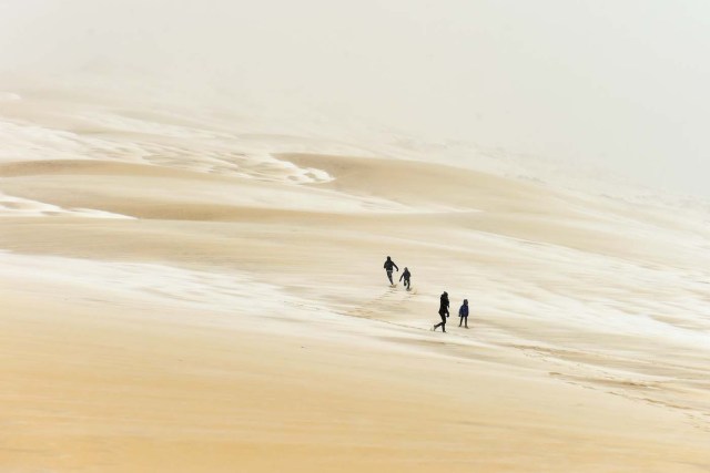 People walk on the partially snow covered Pilat (or Pyla) sand dune after snow fall on February 28, 2018 in La Teste-de-Buch, southwestern France. Europe remained on February 28 gripped by a blast of Siberian weather, accounting for at least 24 deaths and carpeting palm-lined Mediterranean beaches in snow. / AFP PHOTO / Nicolas TUCAT
