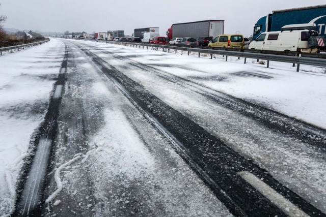 Cars and trucks are stuck in a traffic jam on the snow and ice-covered A9 highway in the direction of Montpellier, near Sete, southern France, on February 28, 2018. Europe remained on February 28 gripped by a blast of Siberian weather, accounting for at least 24 deaths and carpeting palm-lined Mediterranean beaches in snow. / AFP PHOTO / Laurent EMMANUEL