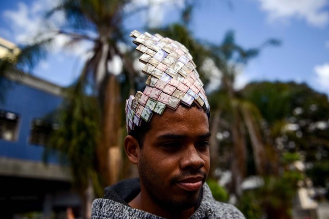 A man tries on a paper crown made by Venezuelan Wilmer Rojas out of Bolivar bills, in Caracas on January 30, 2018. A young Venezuelan tries to make a living out of devalued Bolivar banknotes by making crafts with them. / AFP PHOTO / FEDERICO PARRA