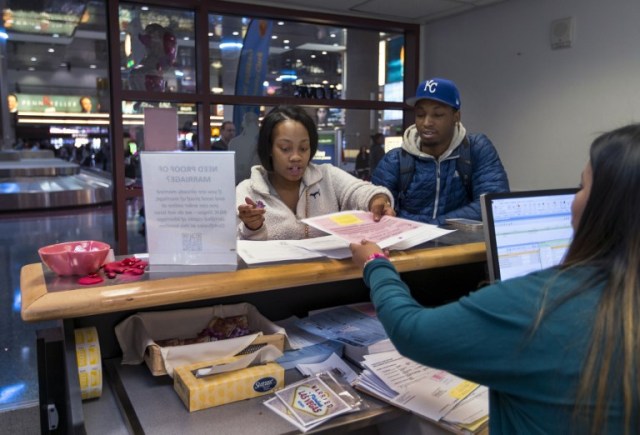 Teaira Thompson and James Anderson of Burlington, Iowa, complete their paperwork as the Clark County Clerk's Office operates a temporary pop-up marriage license office at McCarran International Airport in Las Vegas on February 12, 2018. The Las Vegas airport has given new meaning to rushing to make a connection, offering quickie wedding licenses for lovebirds desperate to get hitched on Valentine's Day. Clark County, the authority that administers Sin City's weddings, has opened a pop-up marriage license bureau by a baggage carousel at McCarran International Airport. / AFP PHOTO / L.E. Baskow / TO GO WITH AFP STORY, "Valentines get quickie marriage licenses at Las Vegas airport"