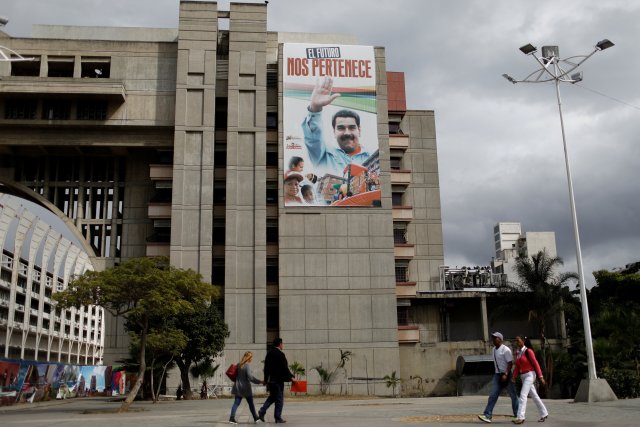 People walk past a banner depicting Venezuela's President Nicolas Maduro that reads "The future belongs to us" in downtown Caracas, Venezuela February 1, 2018. Picture taken February 1, 2018. REUTERS/Marco Bello