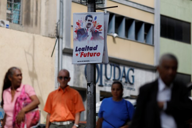 Personas caminan frente a una pancarta que representa al presidente de Venezuela, Nicolás Maduro, que dice "lealtad y futuro" en el centro de Caracas, Venezuela, el 1 de febrero de 2018. REUTERS / Marco Bello