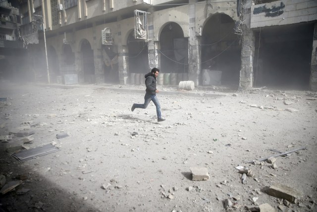 En la imagen, un hombre corre tras un bombardeo en la población de Douma en Ghouta oriental en Damasco, el 6 de febrero de 2018. REUTERS/ Bassam Khabieh
