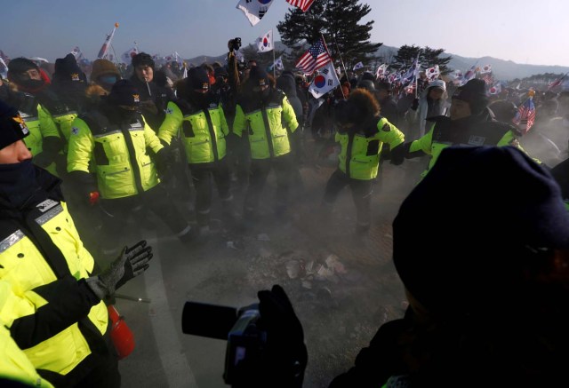 Police rush to extinguish burnt portraits of North Korean leader Kim Jong Un during an anti-North Korea protest before the opening ceremony for the Pyeongchang 2018 Winter Olympics in Pyeongchang, South Korea, February 9, 2018. REUTERS/Edgar Su