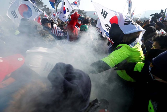 Police (in green) try to stop demonstrators from burning portraits of North Korean leader Kim Jong Un during an anti-North Korea protest before the opening ceremony for the Pyeongchang 2018 Winter Olympics in Pyeongchang, South Korea, February 9, 2018. REUTERS/Edgar Su