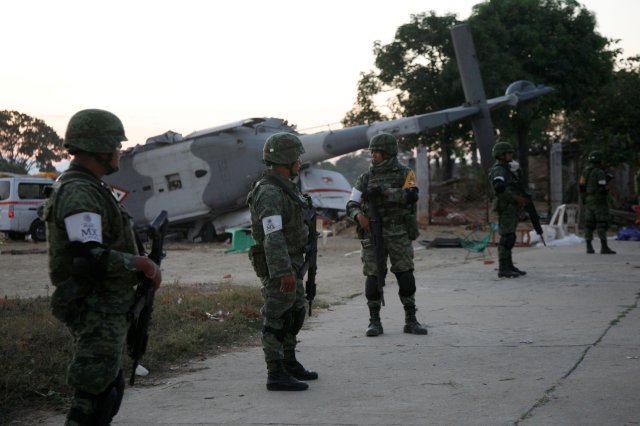 Soldiers stand guard next to a military helicopter, carrying Mexico's interior minister and the governor of the southern state of Oaxaca, crashed on top of two vans in an open field while trying to land in Santiago Jamiltepec, Mexico February 17, 2018. REUTERS/Jorge Luis Plata NO RESALES. NO ARCHIVES.