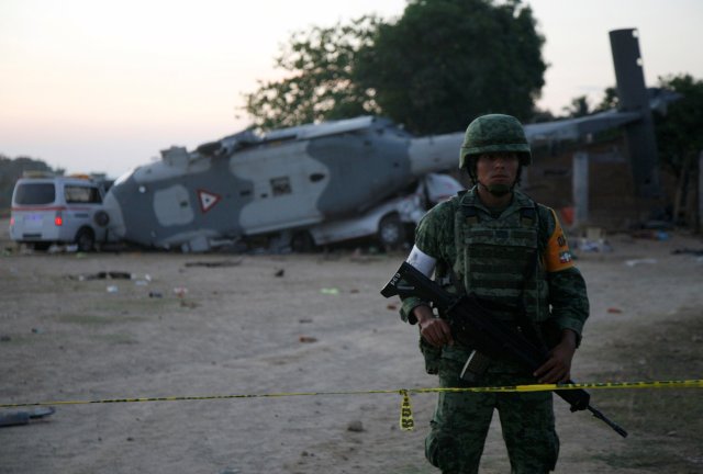 A soldier stands guard next to a military helicopter, carrying Mexico's interior minister and the governor of the southern state of Oaxaca, crashed on top of two vans in an open field while trying to land in Santiago Jamiltepec, Mexico February 17, 2018. REUTERS/Jorge Luis Plata NO RESALES. NO ARCHIVES.