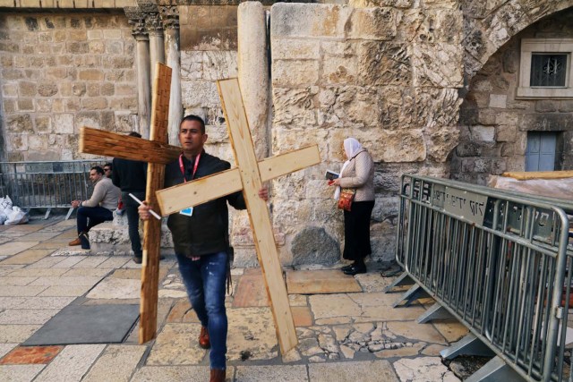 A man carries wooden crosses, near the entrance to the Church of the Holy Sepulchre, in Jerusalem's Old City, February 28, 2018. REUTERS/Ammar Awad